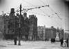 [O'Connell Street between Abbey Street corner and the G.P.O., buildings shelled, street closed off, statue of William Smith O'Brien intact, tram lines]
