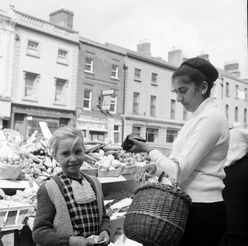[Shopper with basket, young girl, Moore Street Market, Dublin]