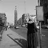 [Nun waiting at bus stop, Parnell Monument in distance, Parnell Street, Dublin]