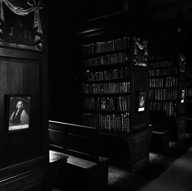 [Interior of Marsh's Library showing framed portraits hanging on bookshelves, St. Patrick's Close, Dublin]