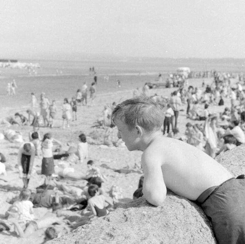 [Boy leaning over wall, crowd on strand, Sandymount, Co. Dublin]
