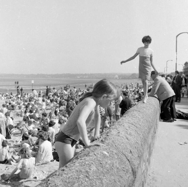 [Girl walking on wall, crowd on strand, Sandymount, Co. Dublin]