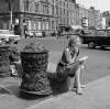 [Young girl seated near ornate ironwork bollards, O'Connell Street, Dublin]