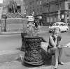 Woman sitting beside ornate ironwork bollards, Parnell Monument, O'Connell Street, Dublin