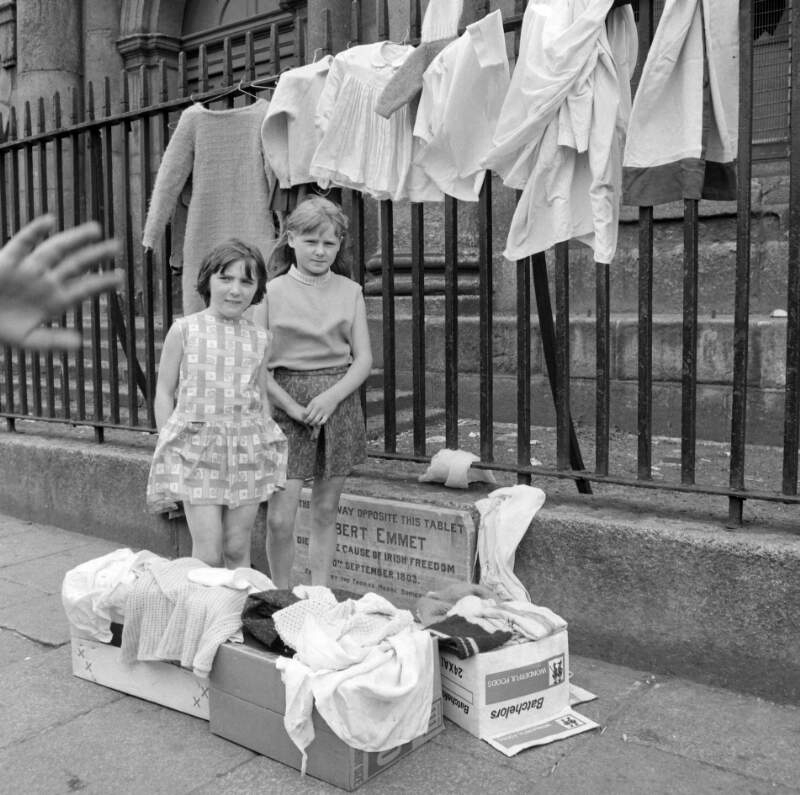[Two little girls surrounded by secondhand clothes, St. Catherine's Church, Thomas Street, Dublin]