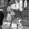 [Elizabeth (Lily) Collins and her friend Angela Arnold, selling secondhand clothes in aid of the charity Gorta as an old woman passes by outside St. Catherine's Church, Thomas Street, Dublin]