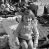 [Girl sitting in cardboard box surrounded by clothes and hats, Cumberland Street Market, Dublin]