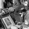 [Boy sitting amongst holy pictures and bric a brac, Cumberland Street Market, Dublin]