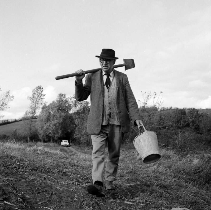 [Patrick Kavanagh walking through field, carrying a bucket and spade, Inniskeen, Co. Monaghan]