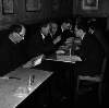 [Patrick Kavanagh reading book, Flann O'Brien gesturing across table, Con Leventhal, John Ryan with head in hands, unidentified man in background, Anthony Cronin at Davy Byrnes pub, Bloomsday, Duke Street, Dublin]