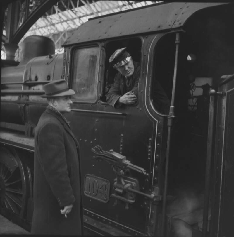 [Frank Spollen standing on platform with train driver looking out of the driving cab, Amien Street railway station, Dublin]