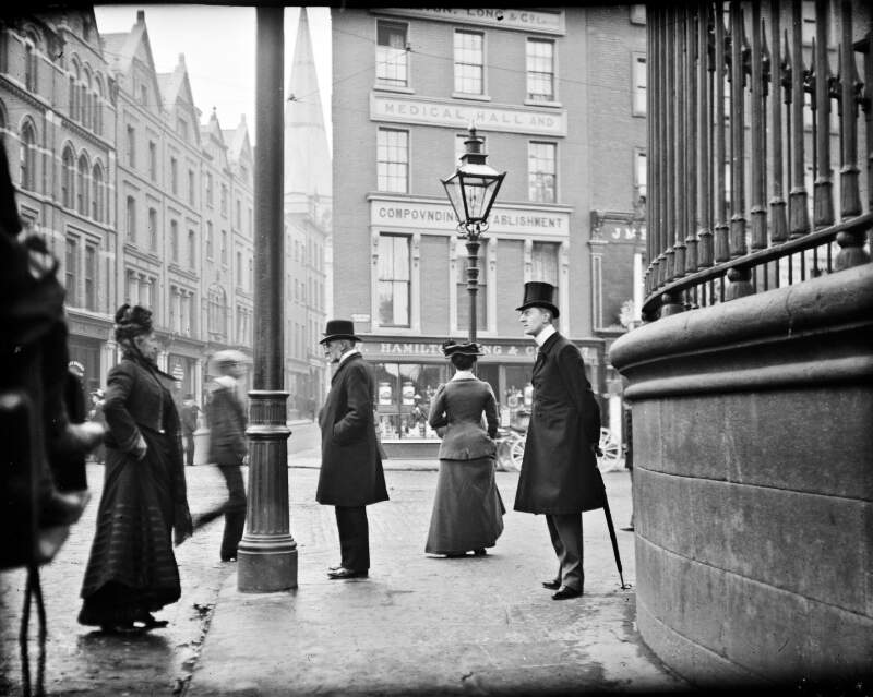 [Man with umbrella standing at the junction of Nassau Street, Grafton Street and Suffolk Street]