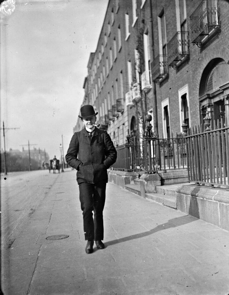 [Young man walking and smoking pipe on Merrion Square]