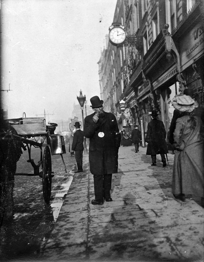 [Cabby walking and smoking pipe outside Nos. 32-33 Westmoreland Street]