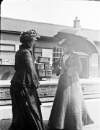 [Two women standing on the platform at a train station]