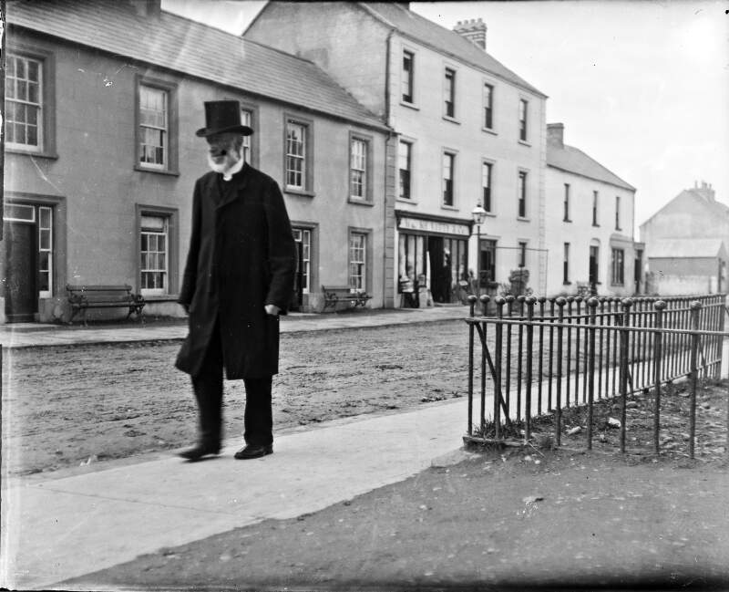 [Man with beard and top hat walking along a road]