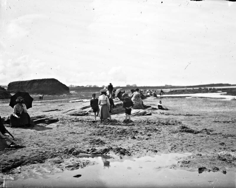 [Children playing with sand at a beach, possibly Bundoran, with people in the background]