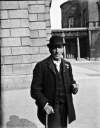 [Man with cane, standing outside the National Library of Ireland and Leinster House, Kildare Street]