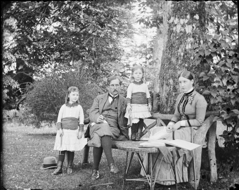 [Lord Cloncrock seated on garden bench with his daughters Georgiana, Edith and Ethel, Clonbrock, Co.Galway]