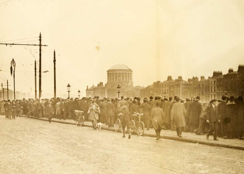 [Crowds gathered on the quays with view of Four Courts in the background]