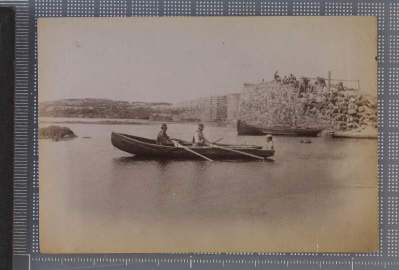 [Two men rowing currach with one passenger]