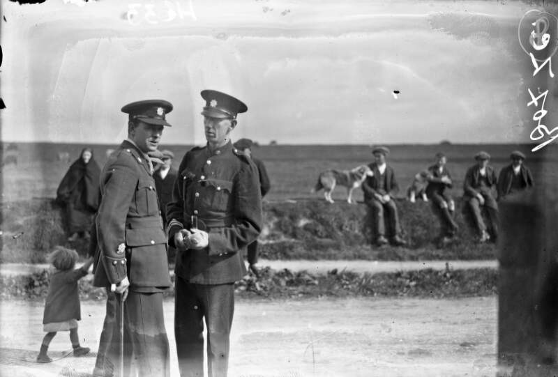 [Two policemen in conversation, following Drumcollogher cinema fire funerals.]