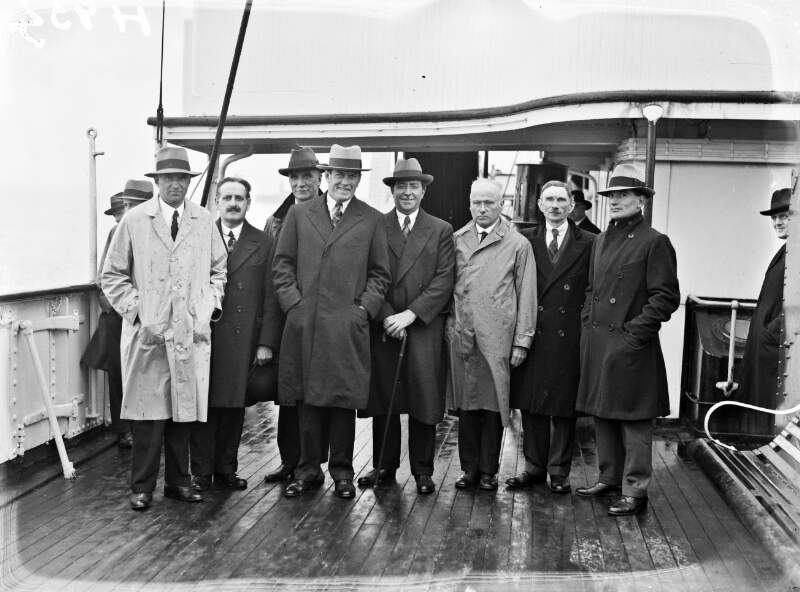 [Boxer Gene Tunney (hands in pockets) with group of men on deck of ship].