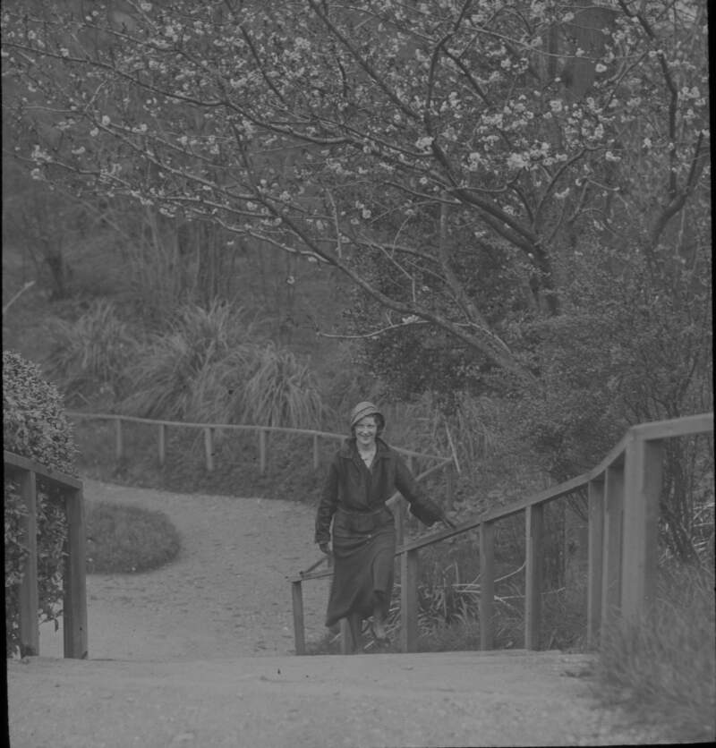 Woman crossing bridge in park/green.