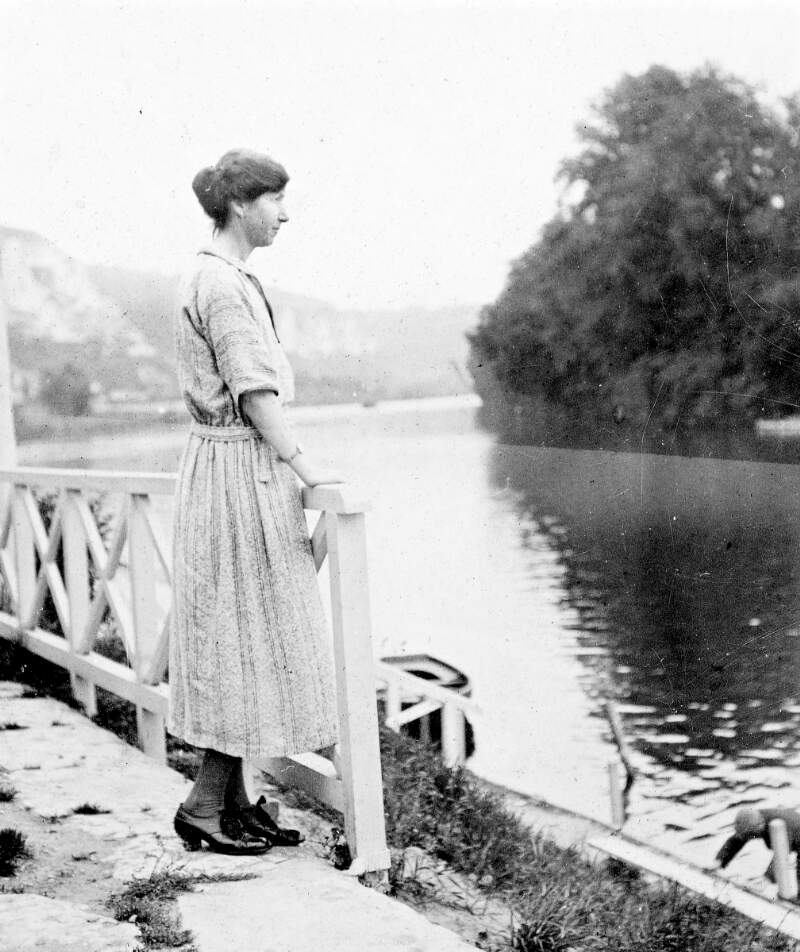 Woman at riverbank, looking across river.