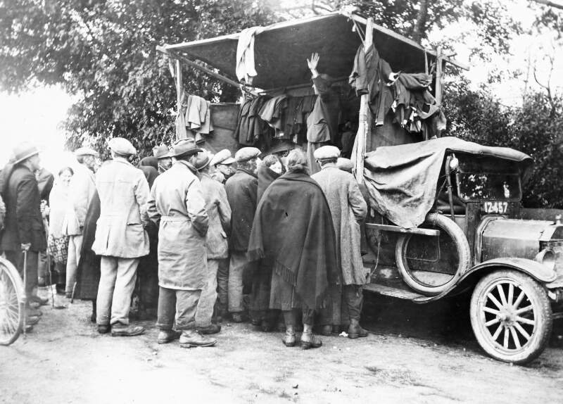 Flatback truck, with clothing. Trader with people looking on.