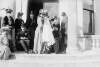 [Christening party on steps of Clonbrock House. Woman standing with baby in christening robes at centre of group.]