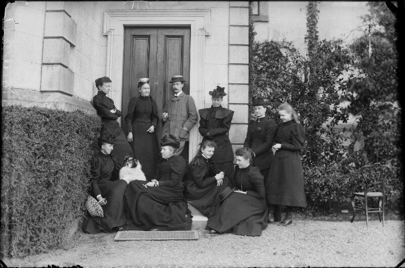[Dillon family group outside house. Nine women and one man, fashions typical of 1880's to 1900's. Includes Augusta Dillon and her daughter Georgiana (seated at front)]