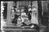 [Group of women in "peasant" style dresses, on steps of Clonbrock House. Younger women wearing bonnets and floral print dresses.]