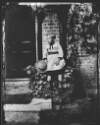 [Young boy seated outside photograph house, wearing tunic and holding straw boater style hat, similar to Clon 191]