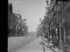 [Dame Street decorated with flags and bunting. Trinity College in the distance, people on pavements, trams also visible, maybe on the occasion of a royal visit.]