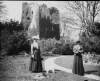 [Castle from Hay's garden Ed and Mops. Two women standing in front of castle/tower overgrown with ivy. Both women carry box cameras, one possibly Edith Dillon(b.1878) Small white dog also visible. Garden is that of Willie Hay, the steward at Clonbrock House.]