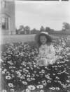 [Ursula Mahon, the daughter of Edith Dillon and Sir William Mahon c.1910. Young girl sitting in field of flowers, house in background.]