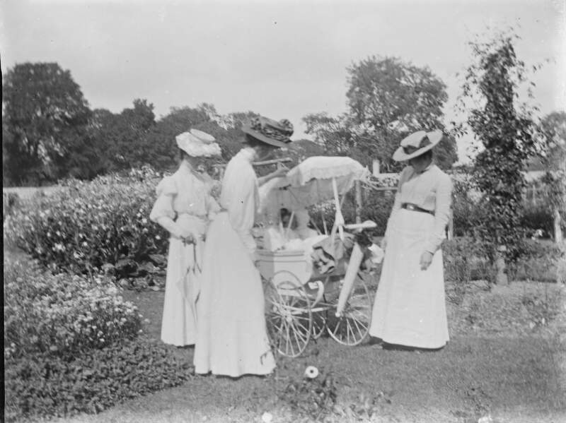 [Three women gazing at child in pram, possibly Ursula in the pram, while one of the women could be Augusta Crofton.]