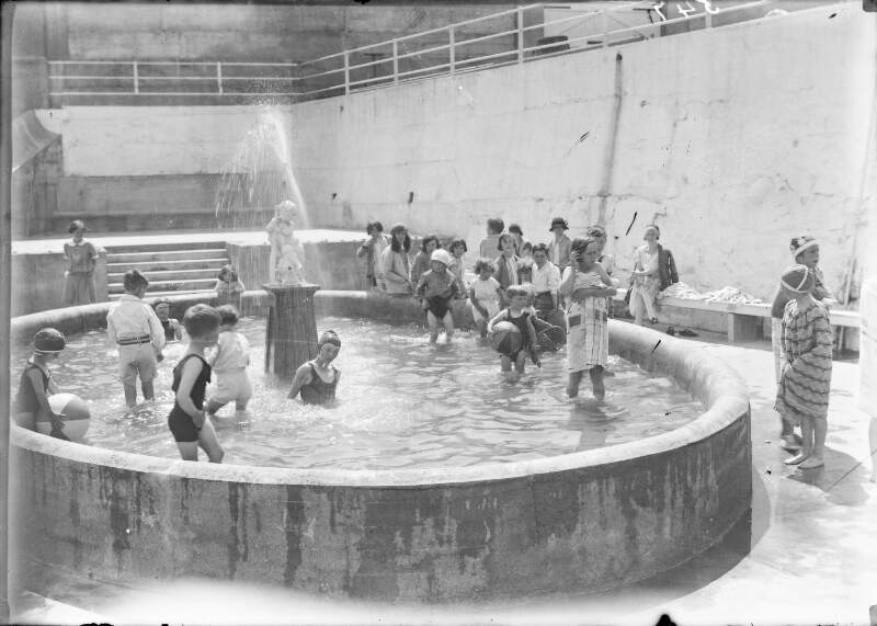 [Children in bathing costumes playing in fountain.]
