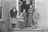 [Family portrait of two women, two boys and young girl and dog in front of entrance.]