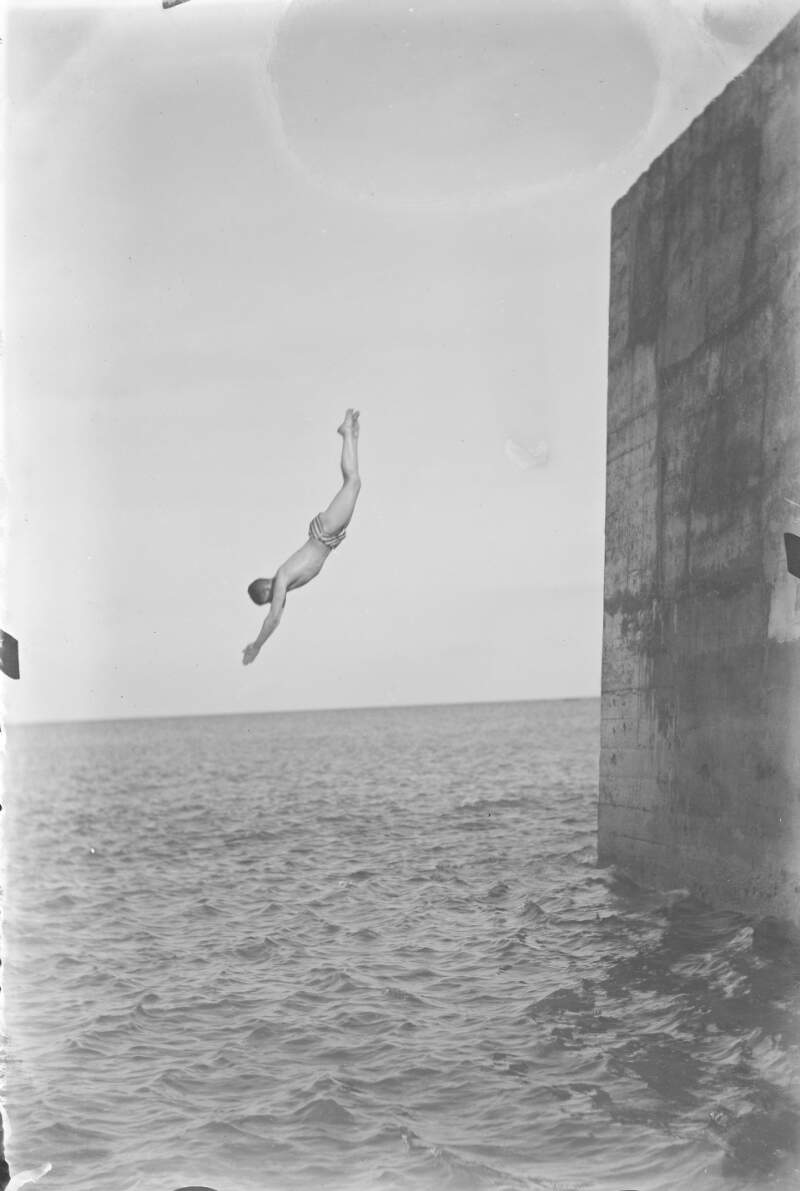 [Boy diving into sea from a high wall.]
