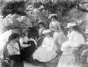 [Bray, c. 1911. Group of women seated on rocks. One of the women has an opened parasol.]