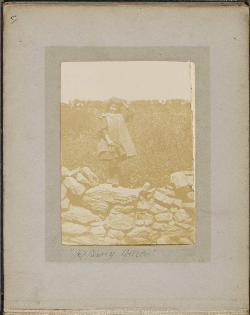 [Young girl, standing on a stone wall],