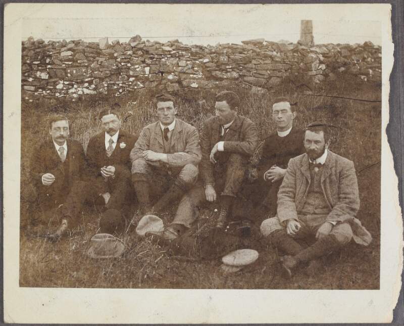 [Arthur Griffith, seated among friends, by a stone wall],