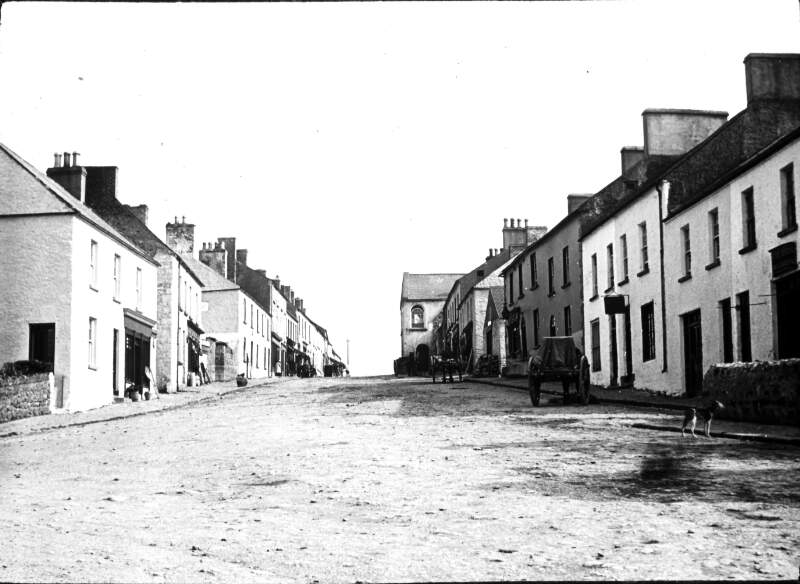 Main Street, Killeshandra, with shops, cars, figures in distance.