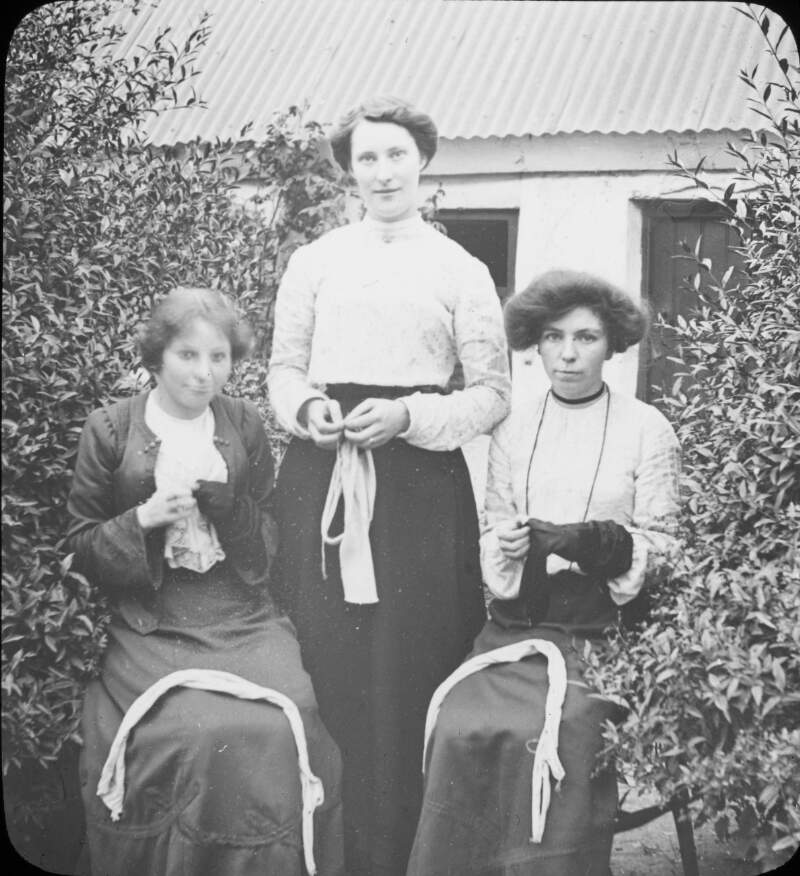 Cottage industry embroiderers, Balbriggan. Three women at gate with goods.
