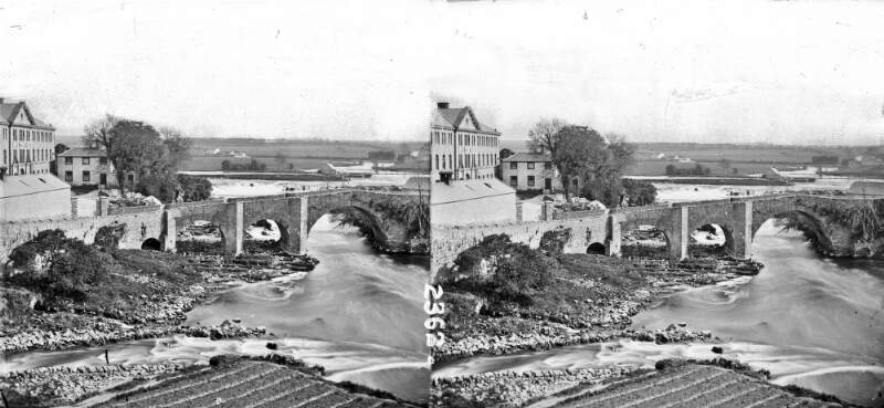 Bridge of four arches, slopes over fast stream, houses in near background; left, river on flat plain in background