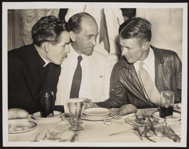 [Fr. Fulton Sheen, Robert Brennan and Douglas 'Wrong Way' Corrigan in discussion at a dinner],