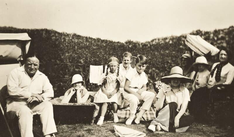 [Group of four women, two men, and three children in garden with deckchairs, unidentified location]
