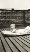 [Billie Carson, six months old, lying on blanket on rooftop